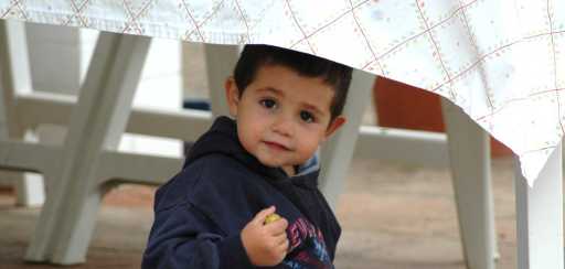 Niño escondiendose bajo una mesa